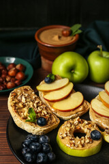 Plate of tasty sandwiches with nut butter, apples and blueberry on wooden table, closeup