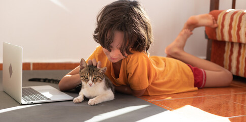 boy plays with a cat during an online lesson. home schooling.