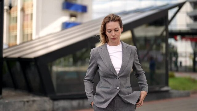 successful businesswoman walks in city center, medium portrait of beautiful lady in suit