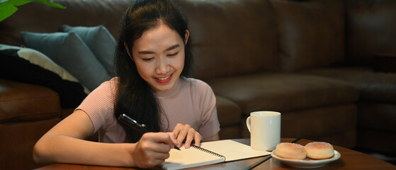 Pleasant woman in casual clothes making important notes, agenda plan planning daily appointment on...