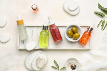 Composition with bottles of essential olive oil and spa stones on light background