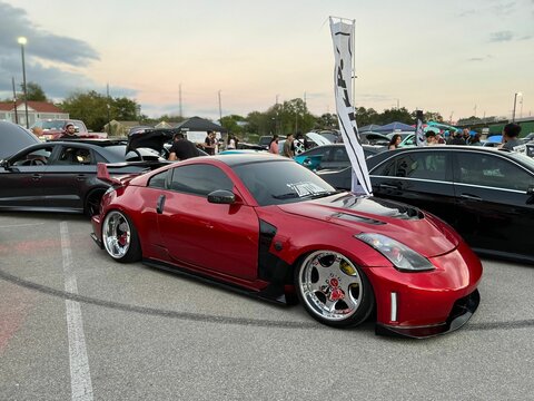 Red sports car Nissan 370z parked on the street with black cars in the background