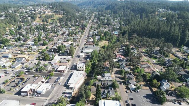 Drone footage of a town with buildings and dense green forests in the background