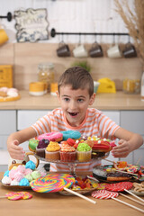 Child and sweet. Happy baby, beautiful little child, fun boy with many sweets. Сhildren love sweets. Happiness in sweets. Child's dream: confectionery. Kid with rainbow sweets. Children's Day. Sugar