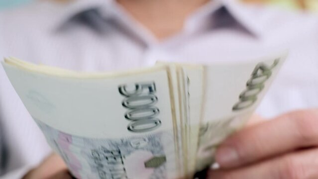 Counting Czech koruna in nominal Five and two thousand banknotes CZK. Hold a cash money on hand. Czechia finance concept. Close up selective focus.