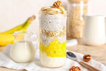 Glass jar of tasty chia seed pudding with banana on light table