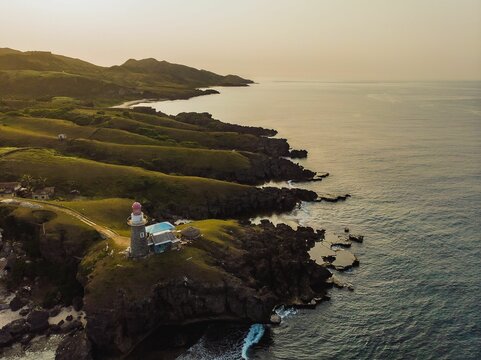 Beautiful view of green hills and the beach at sunset on Batanes island, Philippines.