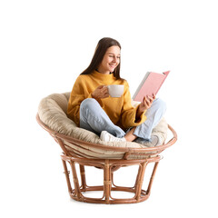 Beautiful woman with cup of cocoa reading book in armchair on white background