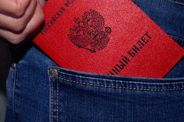 A military ID issued by the Russian Federation is taken out of the back pocket of a jeans close-up.