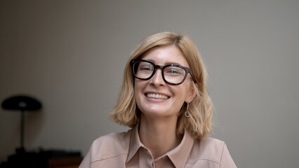 Portrait of blonde woman in eyeglasses smiling. Attractive stylish adult person looking at the camera with sincere and happy smile. Concept of good mood.