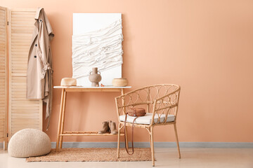 Interior of stylish hall with table, 3D textile artwork and armchair