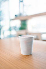 Paper coffee to go cup on a wood table in coffee shop. 