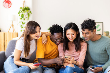 Young millennial group of multiracial friends having fun using mobile phone at home