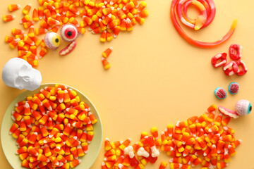 Frame made of Halloween jellies and human skull on beige background