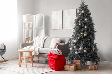 Interior of living room with Santa bag, sofa and Christmas tree