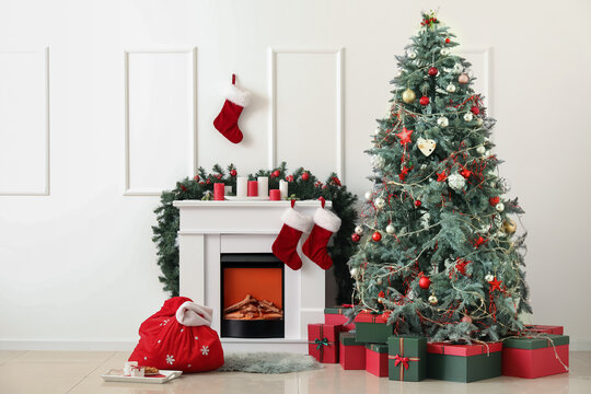 Interior of light living room with Santa bag, fireplace and Christmas tree