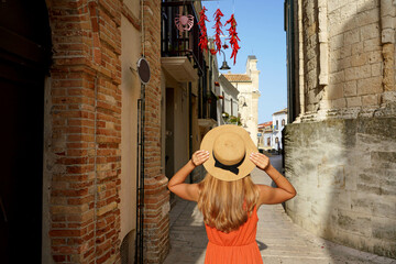 Attractive traveler woman looking at chilli peppers hanging on balcony visiting an historic town of...