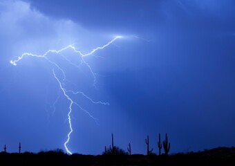 Lightning bolt thunderstorm in a blue sky and silhouettes of cacti in North Scottsdale, Arizona
