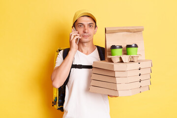 Image of serious delivery man with thermo backpack in white T-shirt and cap, standing with pizza an...