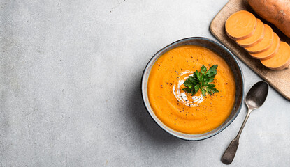 Sweet potato soup in a ceramic bowl, top view, copy space, banner