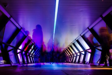 Of people like ghosts in colorful Crossrail place with light effects, long exposure