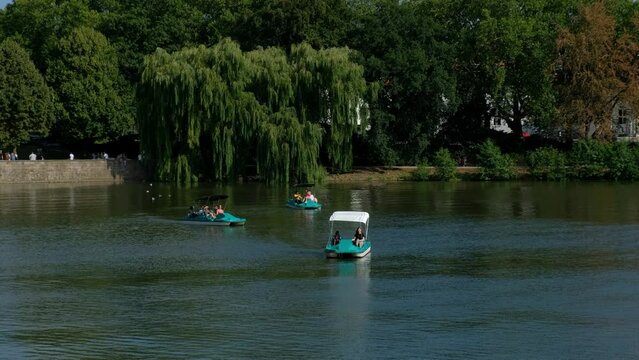 Lake Aasee is in the center of town. People on their day off relaxing floating catamarans on the water.