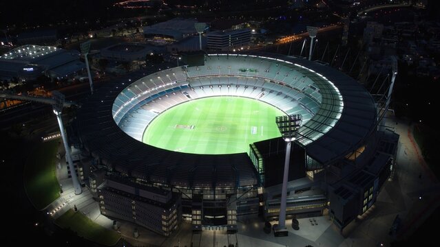 Aerial of the MCG sports stadium in Melbourne lighted up at night.