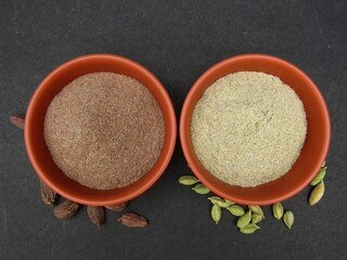 Black cardamom and green cardamom powder in bowls 