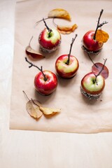 red apples in caramel, sprinkled with nuts, on a light plywood background