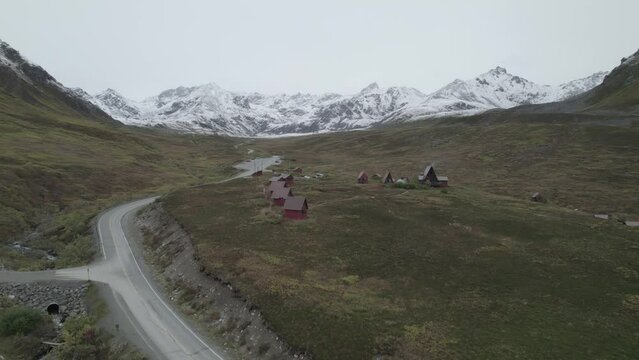 Drone view of Hatcher Pass in Alaska, snow covered mountain pass with greenery field and road