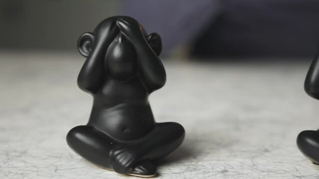 Beautiful shot of see no evil hear no evil speak no evil monkeys with man talking in background