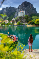 beautiful long-haired girl in a purple dress walks through the town of Omiš with a view of the...