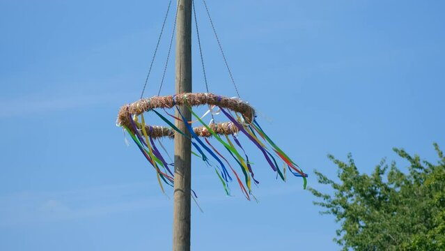 Traditional circle with ribbons on the pole develop in the wind. Maypole Set-Up, Customs With A Long Tradition, Germany.