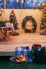 New Year and Christmas backyard decorations. Christmas tree, wreath and gifts. Winter holidays and celebrations. Bonfire and fire. Christmas barbecue