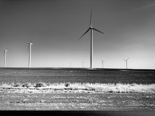 Grayscale of windmill farm in the field with clear sky background