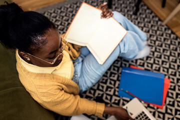 Young African American female student studying at home using laptop.