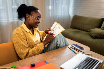 Young African American female student studying at home using laptop.