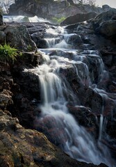 Long exposure vertical shot of Kuhakoski Rapids flowing over rocks under the sunlight