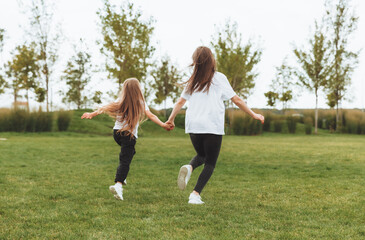 Mother and daughter play and run around the park on a beautiful day. the family is having fun in the park on the grass. morning jog.