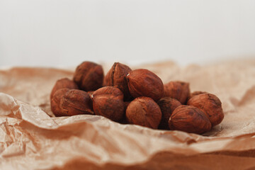 Dry hazelnuts on craft paper, nut without shell on wooden table