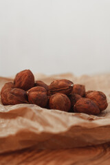 Dry hazelnuts on craft paper, nut without shell on wooden table