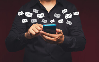 Bsinessman holding a smartphone receives a new message with email icons while standing in the office