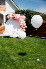 Vertical shot of a banner with pink and white balloons and bench in the garden for a summer party