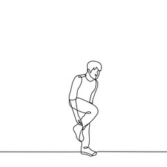 man stands on one leg adjusting his toe on his leg - one line drawing vector. concept to adjust the sock on the go