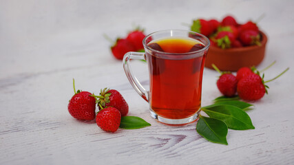 Fresh organic strawberries and black tea in glass cup , over white background. Vegetarian healthy...