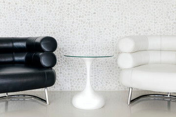 Minimalistic interior design: two leather armchairs (black and white) and glass coffee table