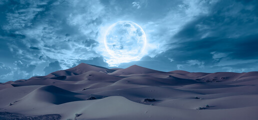 Beautiful landscape with sand dunes in the Sahara desert super blue full moon in the background- Sahara, Morocco 