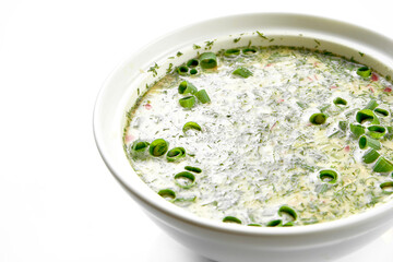 A classic okroshka in a white plate on a white background. Close-up, selective focus