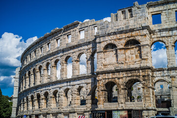 Fototapeta premium Roman amphitheater in the city of Pula, Croatia. Close-ups on the ancient walls of a Roman building. A beautiful sunny day with fairy-tale clouds in the background
