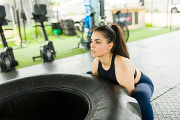 Fototapeta na wymiar Beautiful woman looking strong doing tire flip exercises